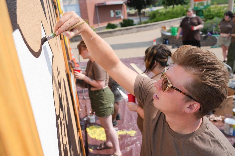 Brad Zenz paints on a building.