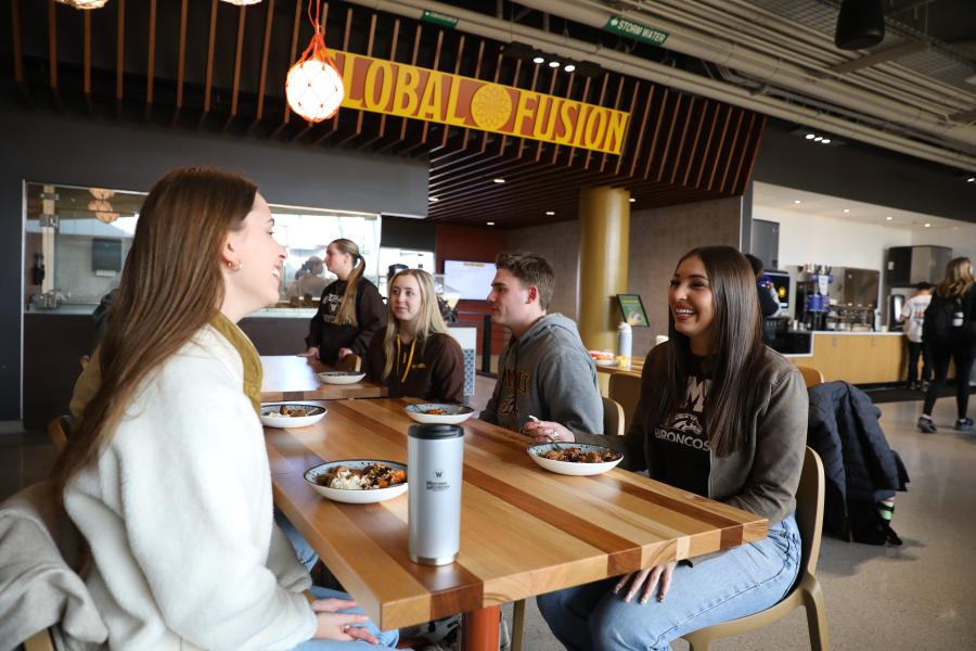 students sitting at table with plates of food in front of global fusion in the SCD