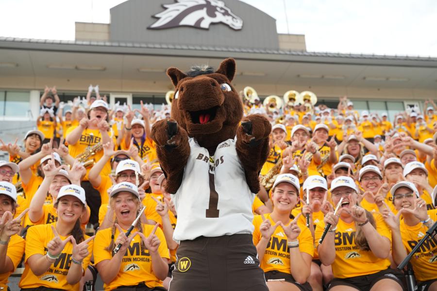 Buster in front of the WMU band at the football field.