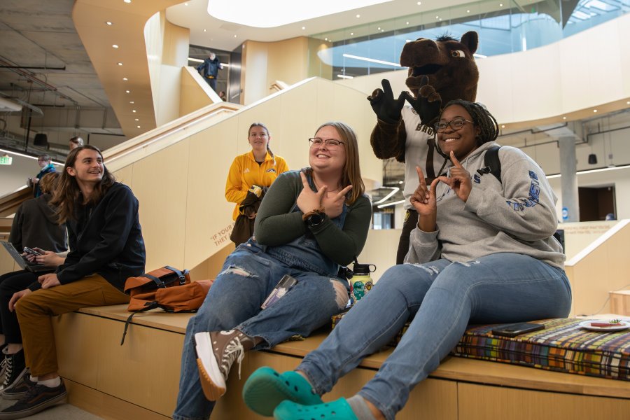 Two students in the Student Center with Buster Bronco showing the Western W on their hands.