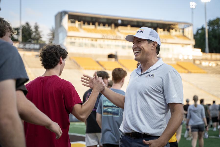 President Russ Kavalhuna high fives students.