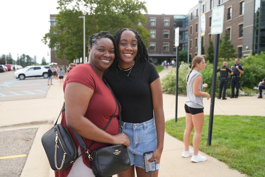 A mother and daughter hug outside.