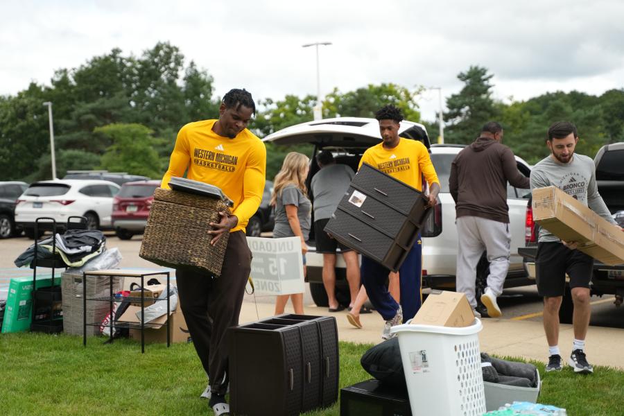 Members of the men's basketball team unload a vehicle.