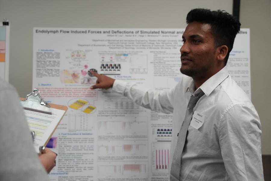 A student showing off their research with a poster presentation. 