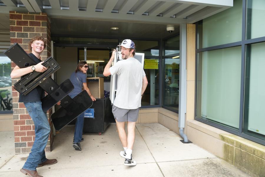 People carry belongings into a residence hall.