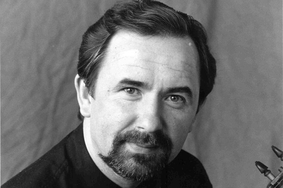 A black and white photo of a smiling man holding a viola.