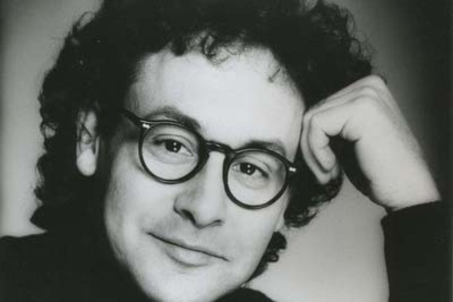 A black and white photo of a smiling man wearing glasses.