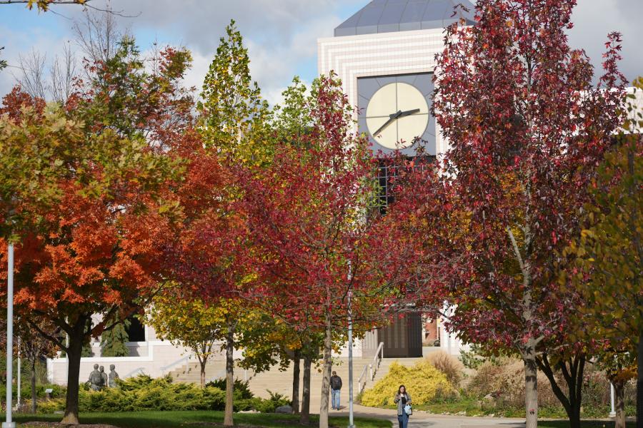 Clock tower peaking over trees with fall-colored leaves.