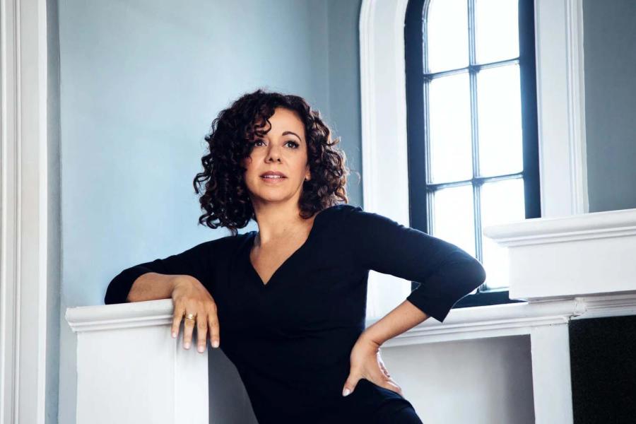 A woman in a black shirt leaning against a railing, looking to the distance.
