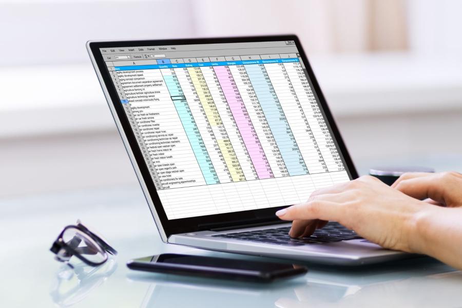 Hands on laptop entering data into a spreadsheet.