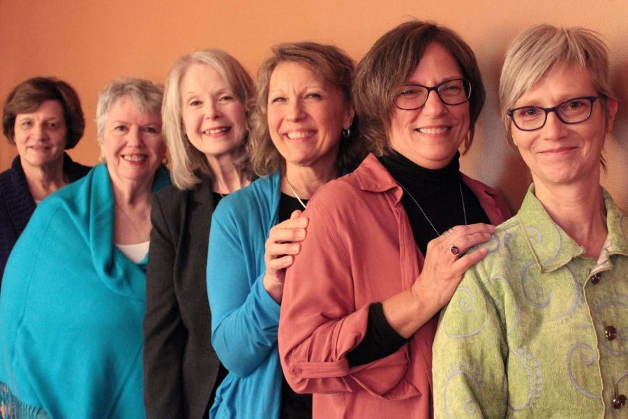 Six smiling women, standing in a line.