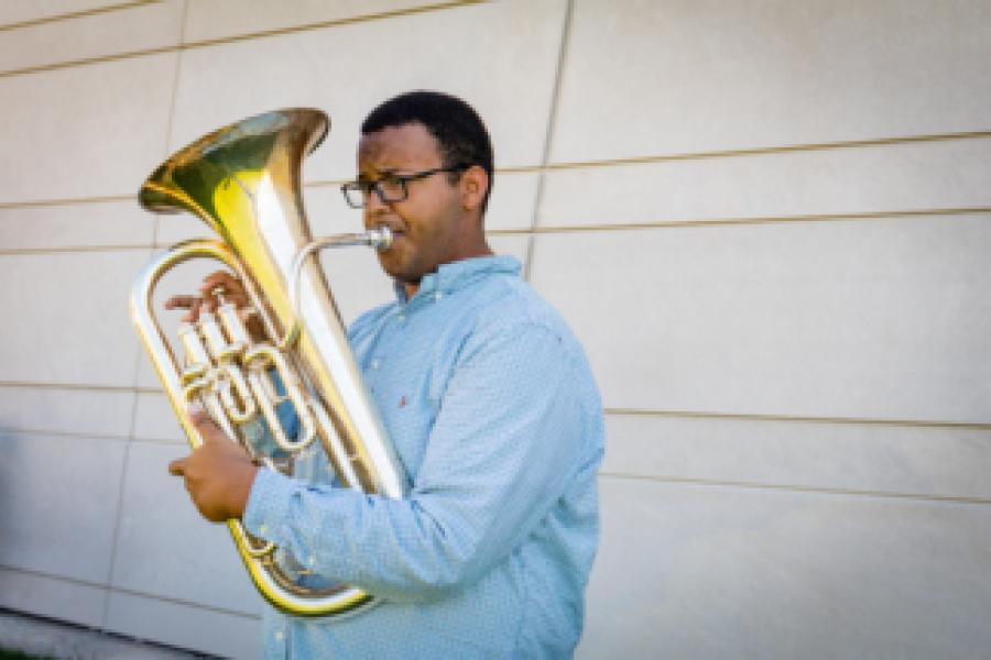 A man in a blue shirt plays the euphonium.