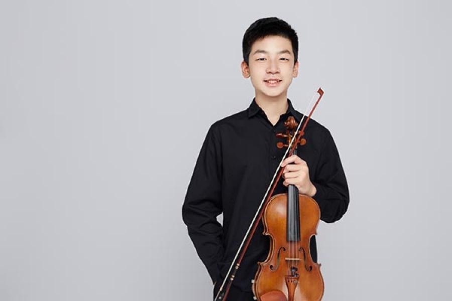 Young smiling violinist holding their instrument.