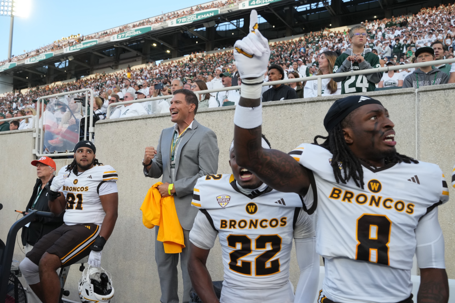 President Russ Kavalhuna stands on the WMU football sideline cheering.