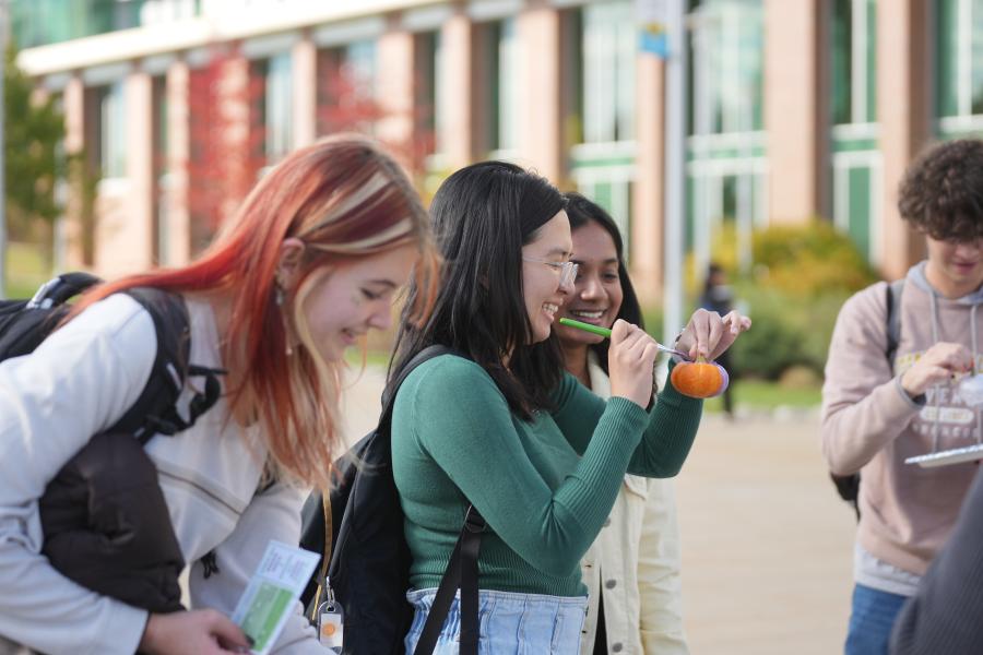 Students painting pumpkins on campus