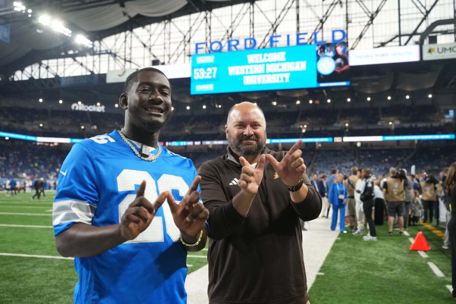 Chris Cheatham and a Detroit Lions player making a "W" with their hands while standing on Ford Field