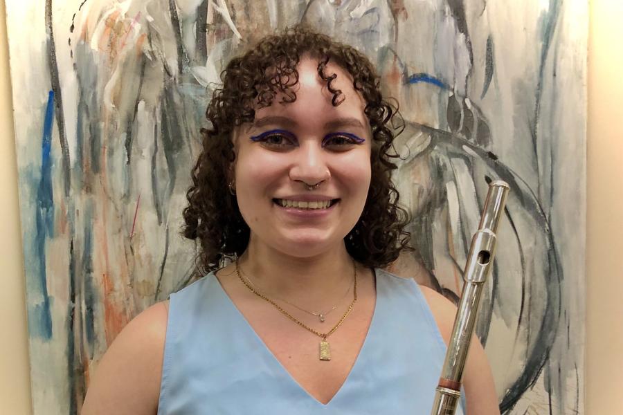 A smiling woman in a blue top, holding a flute.