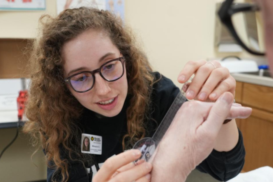 A WMU occupational therapy student, using a tool to take a measurement of a hand