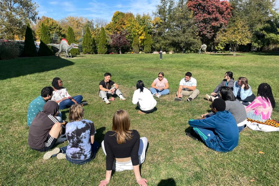 a picture of students sitting in a circle in the grass