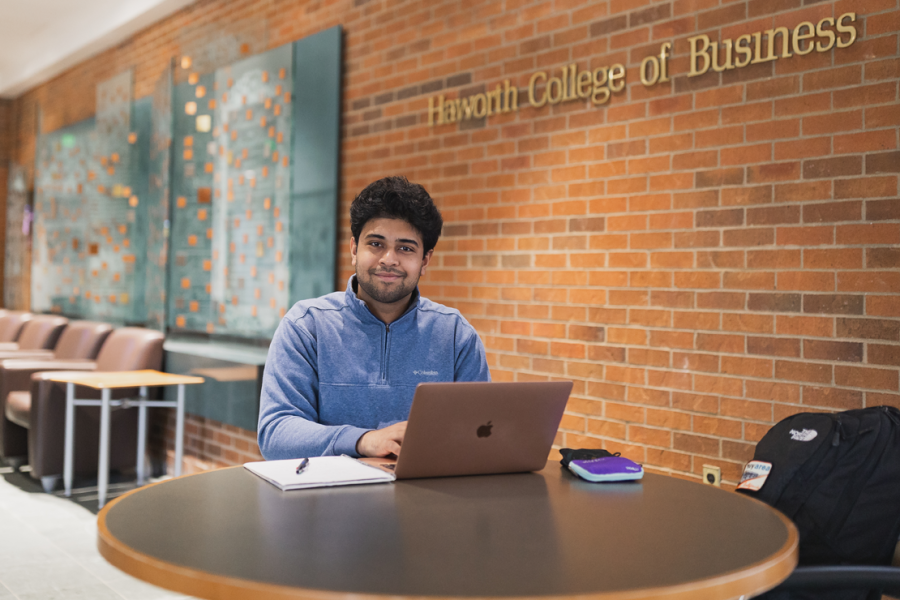 Photo of Raiyan Wasi sitting in the WMU Haworth lobby in a blue zip-up