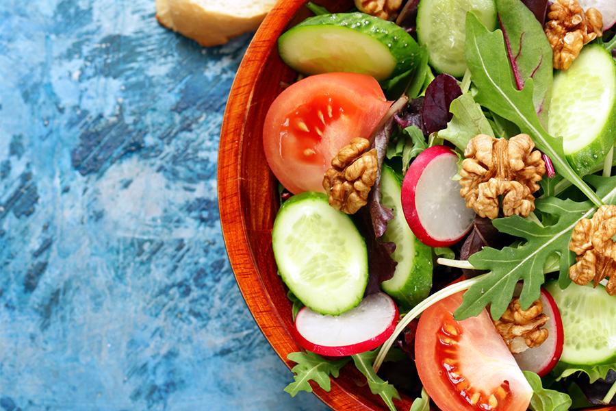 Vegetables on a plate with cucumbers and tomatoes with a blue background