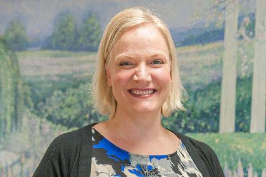 A smiling woman in a blue and black dress.