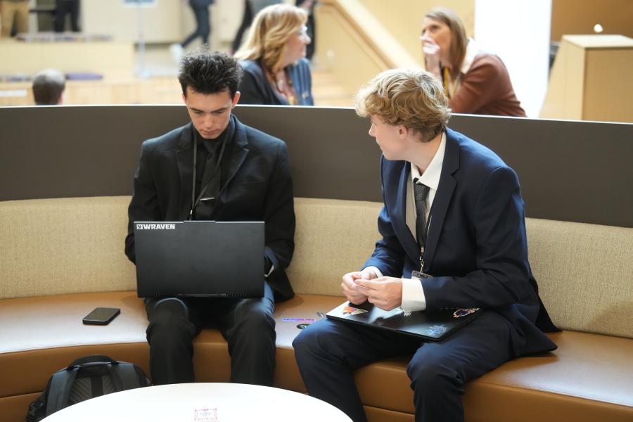 Students sit on a bench with a laptop.
