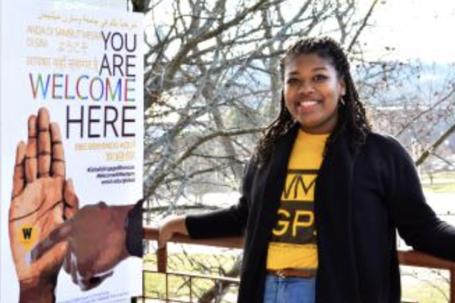 A student next to the poster she designed for the Welcome Here campaign