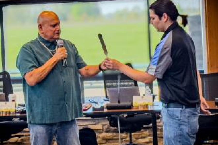 Jordan Morseau, right, receives an eagle feather for his leadership and service on the Pokagon Tribal Youth Council from John Warren, Tribal Council of Elders Representative.