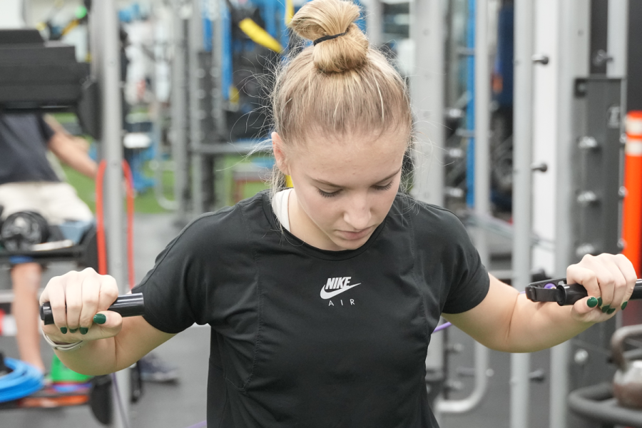 young lady at the weight machine pushing the machine forward