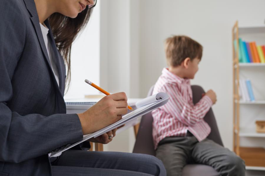 A professional takes notes while a child sits in the background.