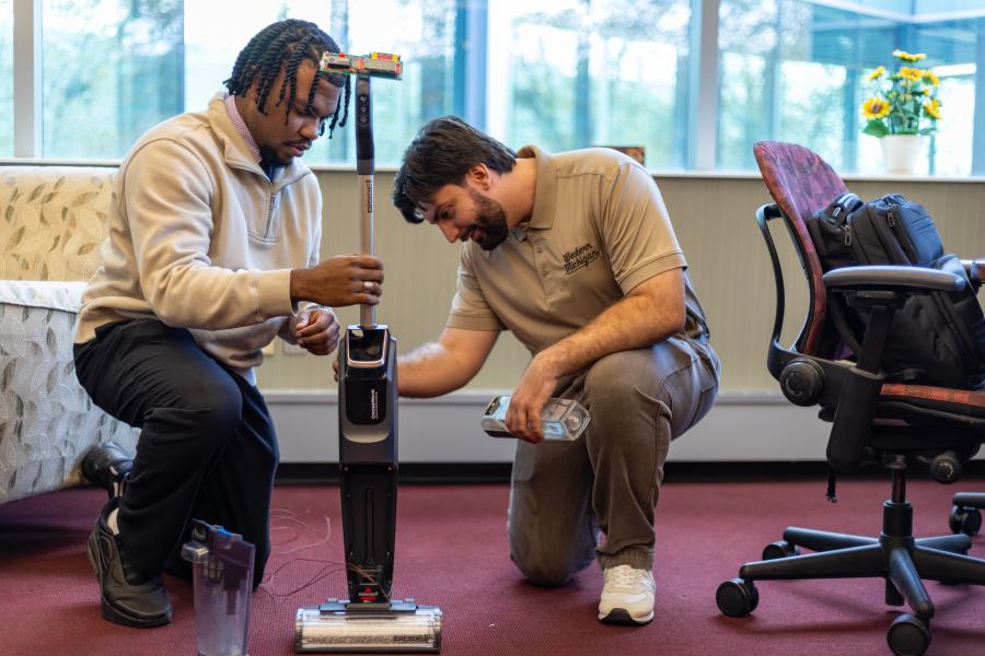 Two students with a vacuum. 