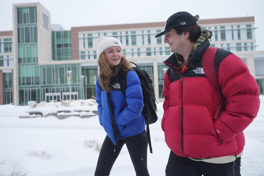 Two students walking outside in the snow outside of Sangren Hall.