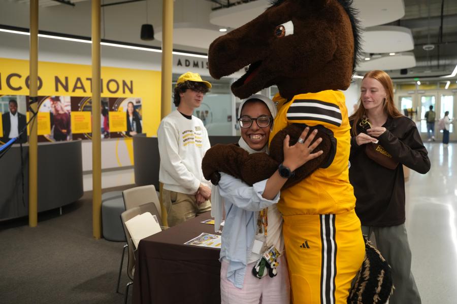 An international student hugging Buster Bronco at International Student Orientation
