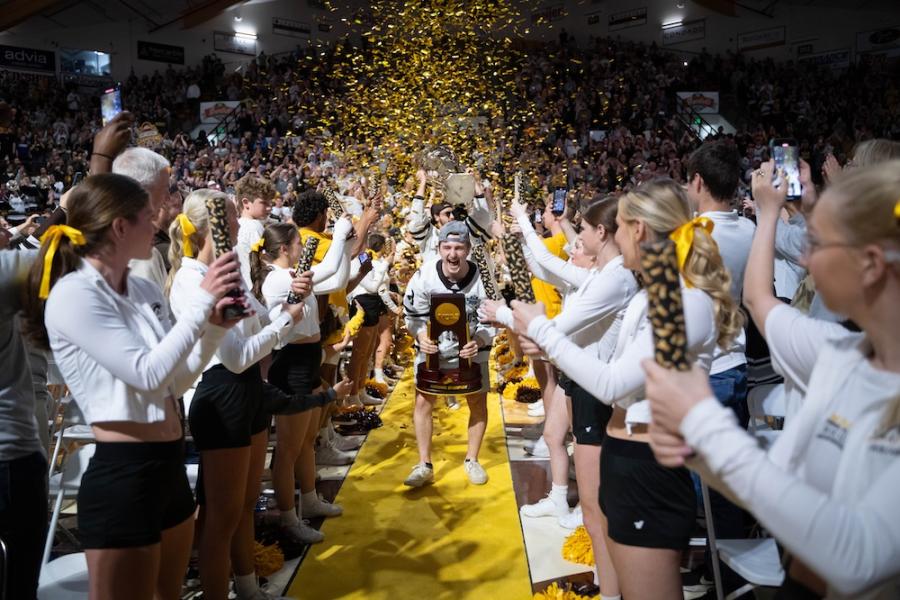 The WMU hockey team carrying the national trophy through a crowd of Bronco fans throwing gold confetti.