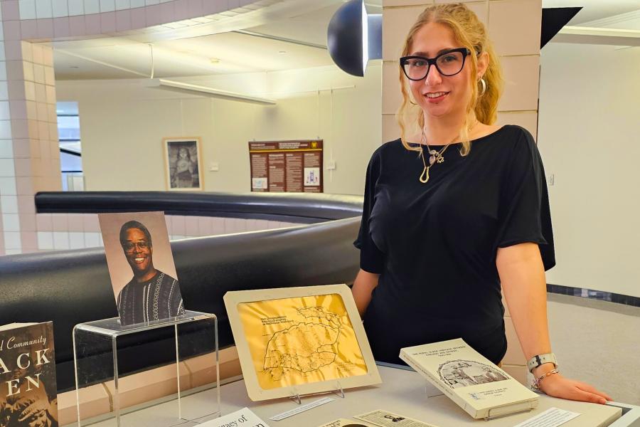 Western Michigan University student Hope Donovan standing next to an exhibit at Waldo Library that they curated with items honoring the legacy of Banjamin C. Wilson.