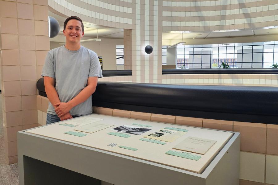 Western Michigan University student Jacob Walsh standing next to an exhibit case they curated at Waldo Library with items from the Dr. Richard Upjohn Light Collection.
