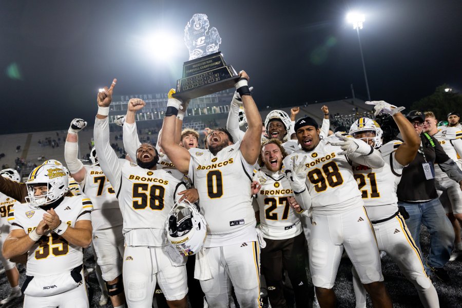 Football players hoist a trophy.