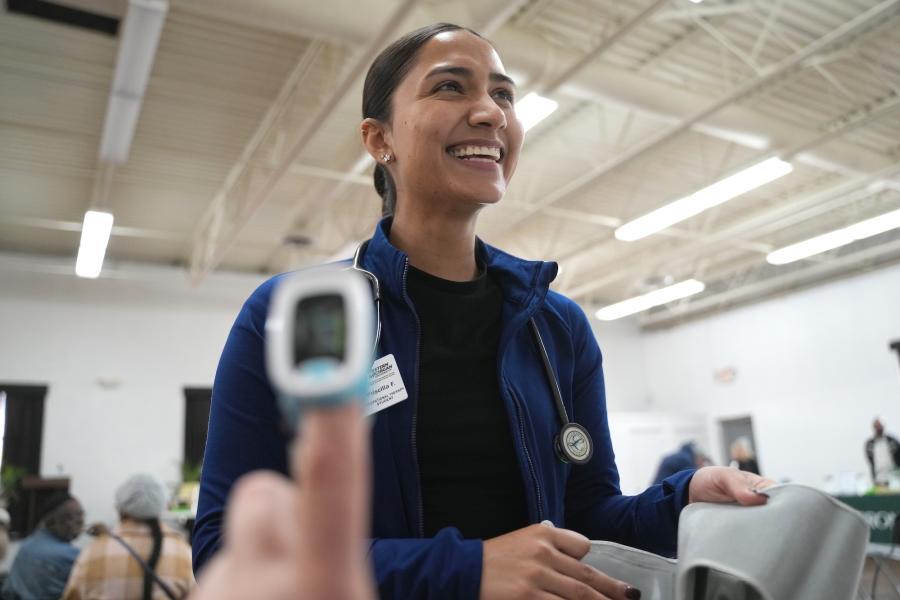A student looking at a computer while someone's heart rate is taken on their finger.