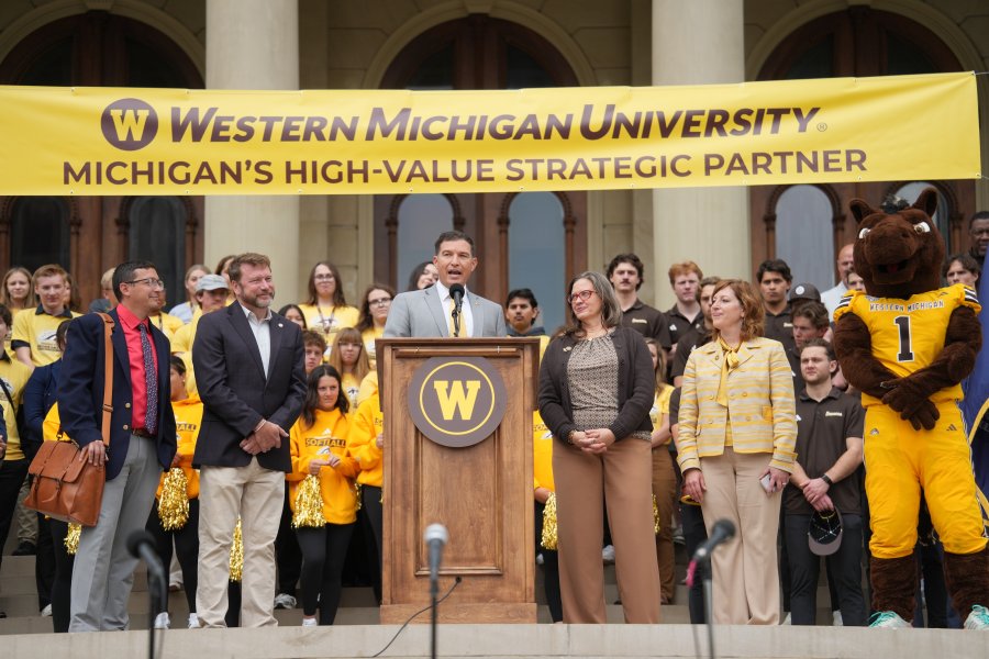 President Russ Kavalhuna talks at a podium on the steps of the Michigan capitol.