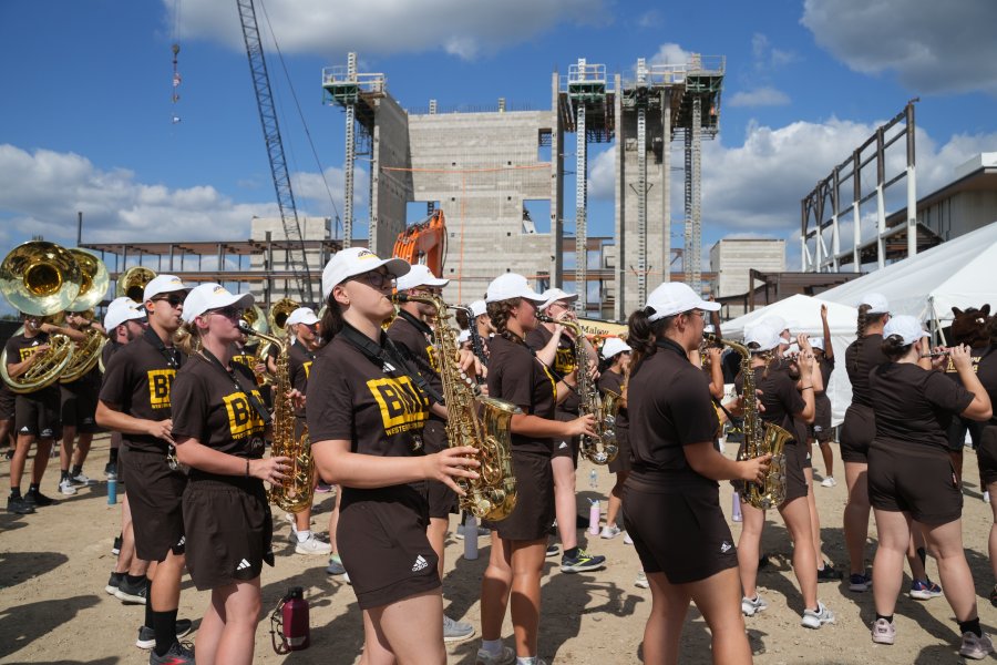 The Bronco Marching Band plays music in front of a construction site.