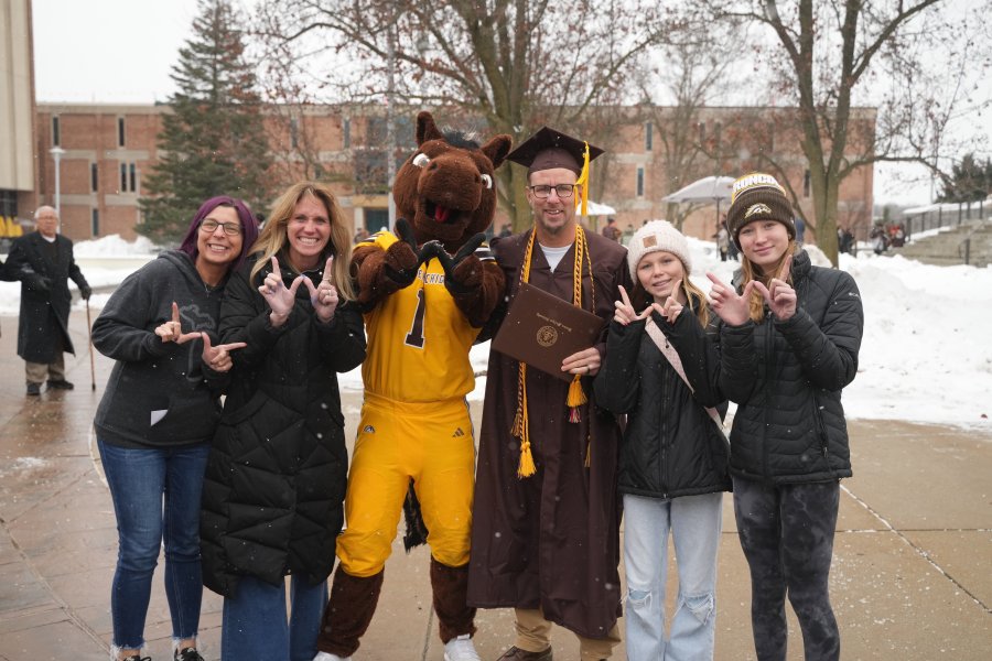 A family poses for a photo outside with Buster Bronco.