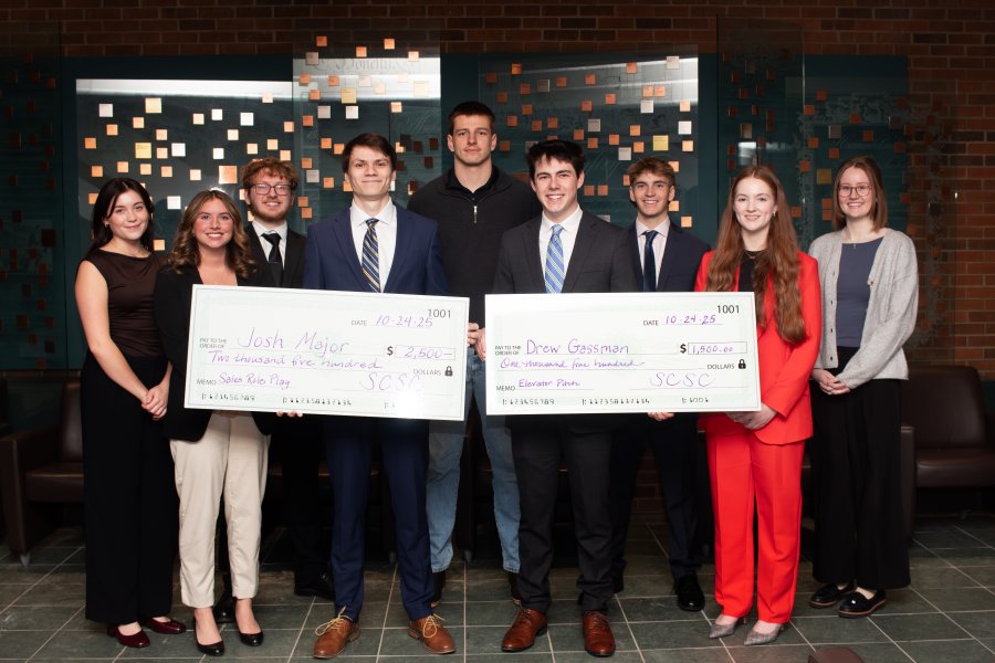 WMU Haworth sales and business marketing students holding up large checks