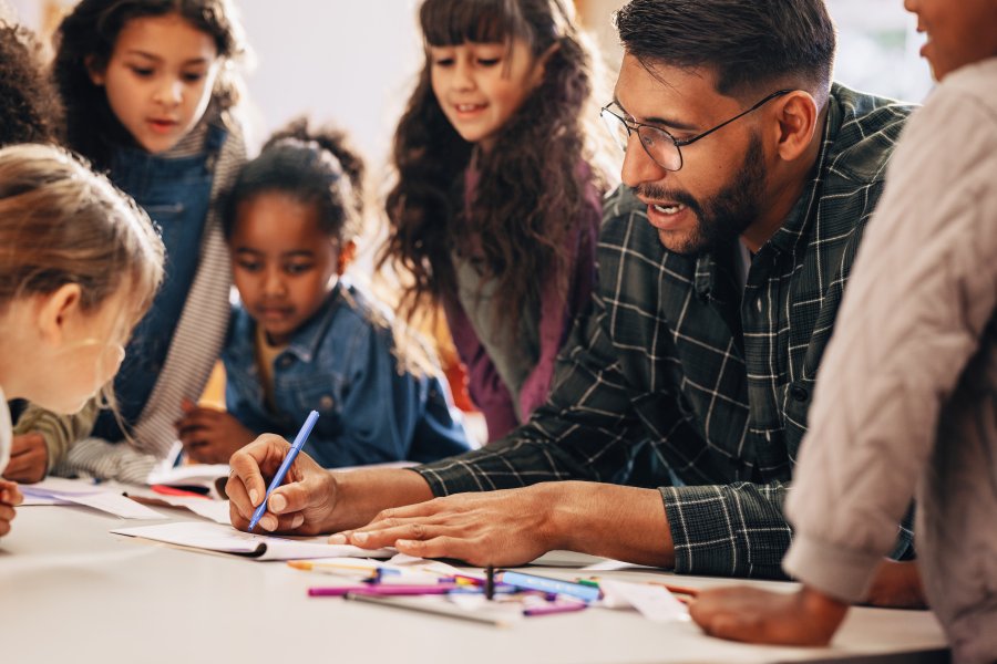 male adult with children drawing on paper