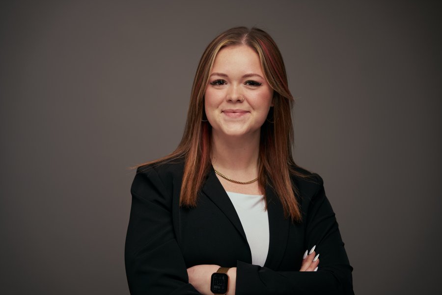 Headshot of Tayler Nanni in a white top and black blazer on a grey background