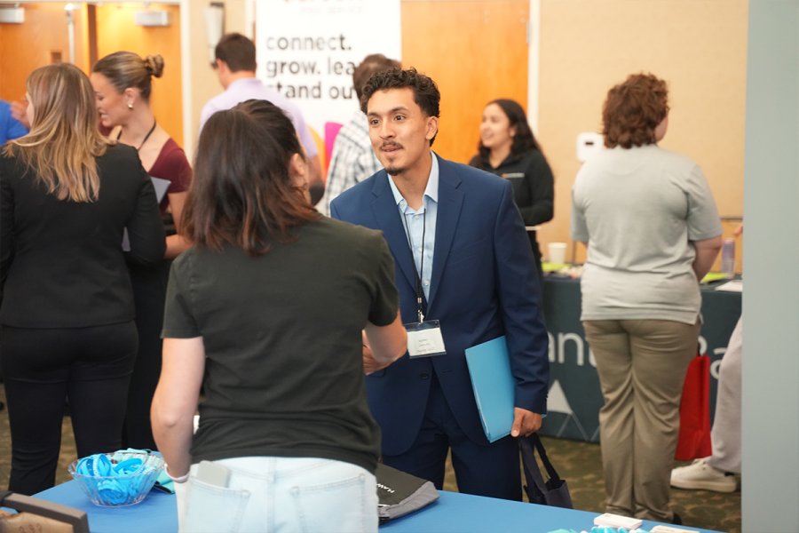 Student shakes hand with an representative of a business at a career fair on the WMU campus