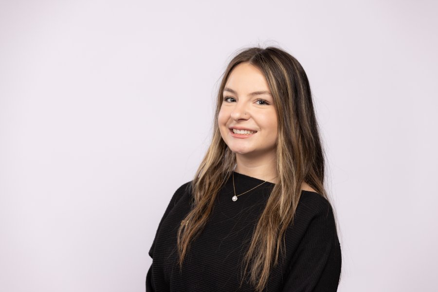 Headshot of Madsion Black in a black blouse on a white background.