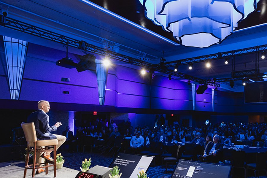 a man standing in front of a large crowd in a conference