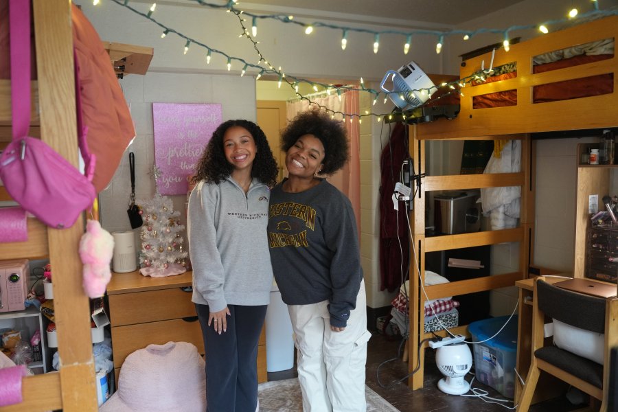 Two students in a pink, decorated residence hall room