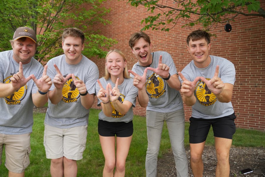 Group of College of Aviation students posing with "W" hands
